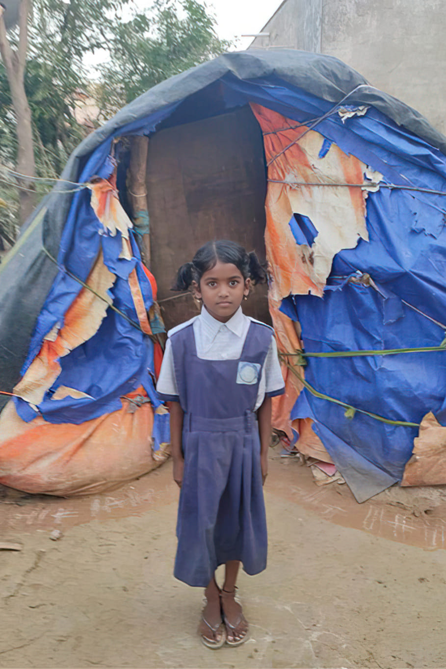 Divena in front of her tarp-covered home