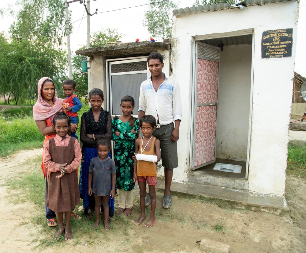 Famille debout devant les toilettes extérieures